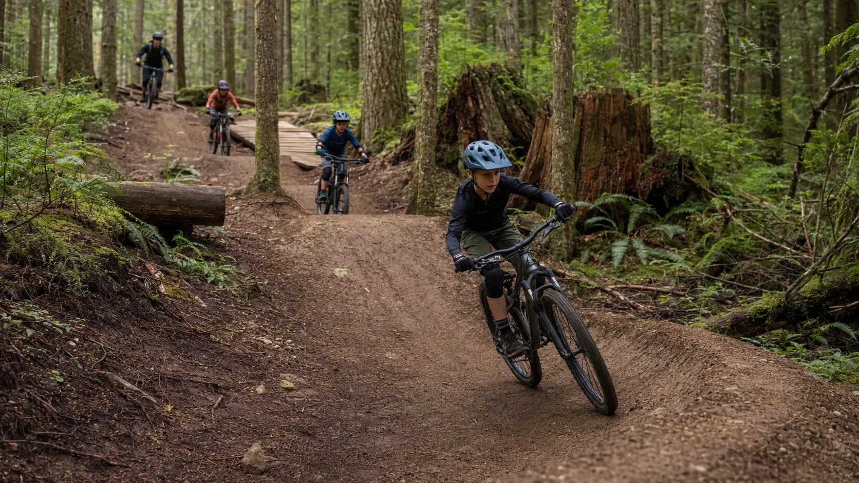 Confident young mountain bikers riding a technical forest trail on Mount Fromme